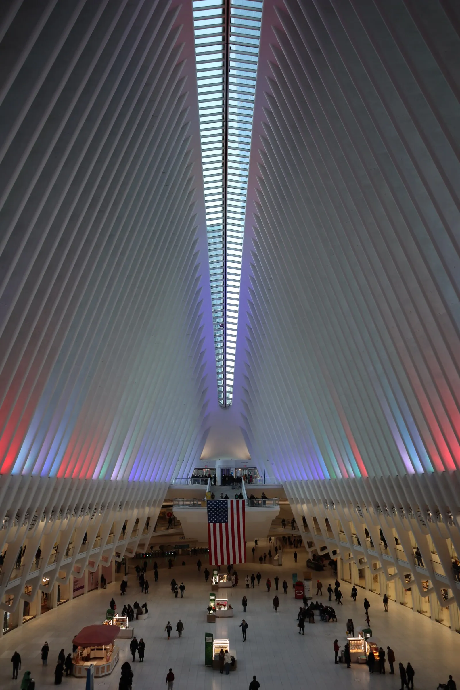 Inside the Oculus, looking down the long white hall to the crowd below.
