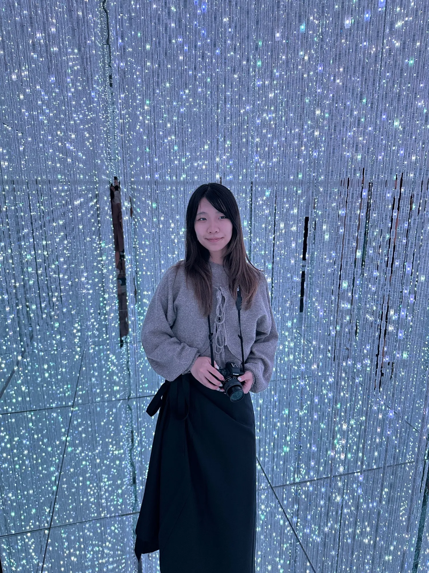 Felena standing in a room full of hanging lights.