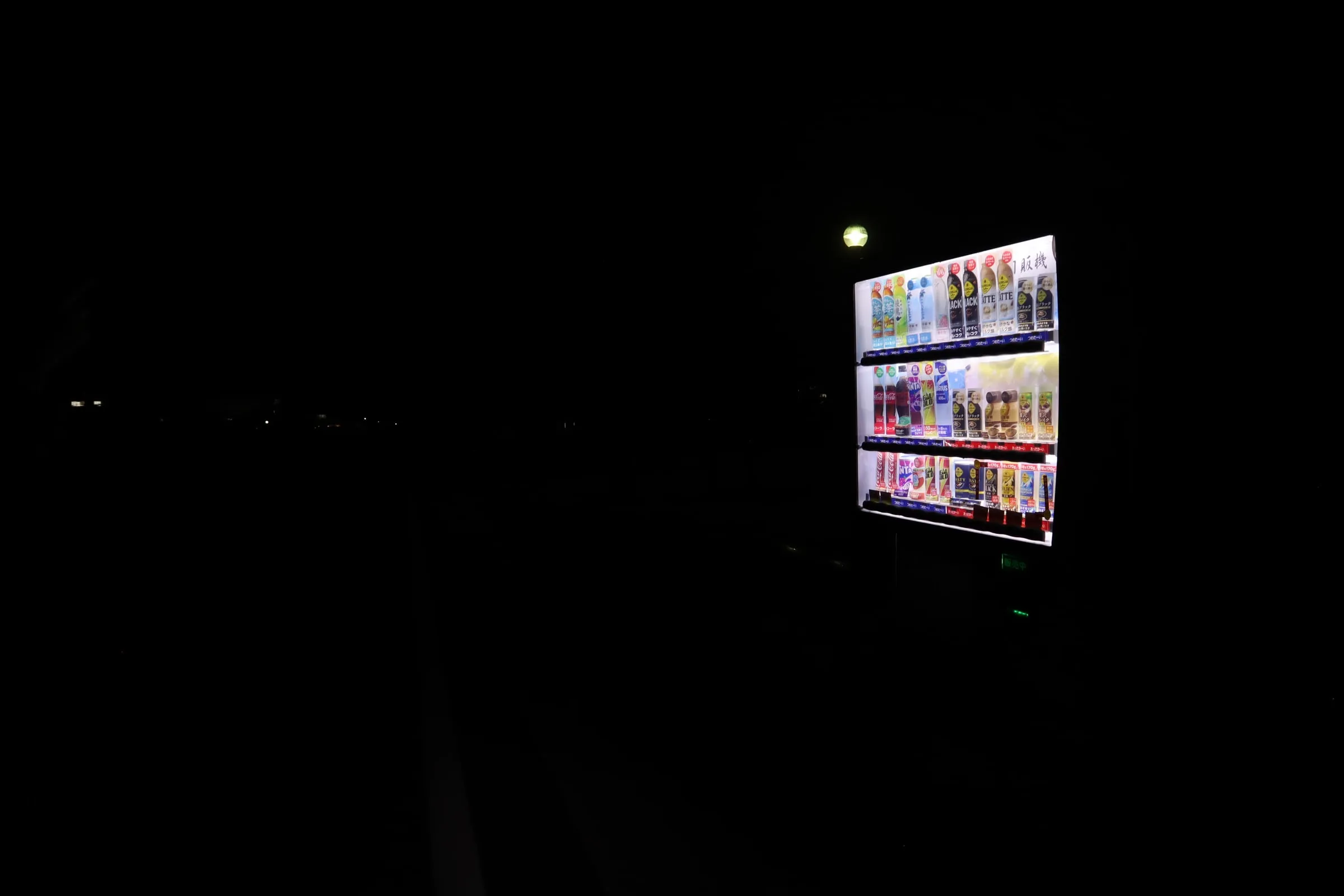 A lit-up vending machine alone in the dark at night.